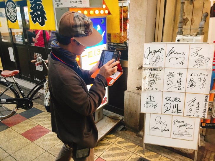 飾られている芸能人のサインを撮る横ちゃん